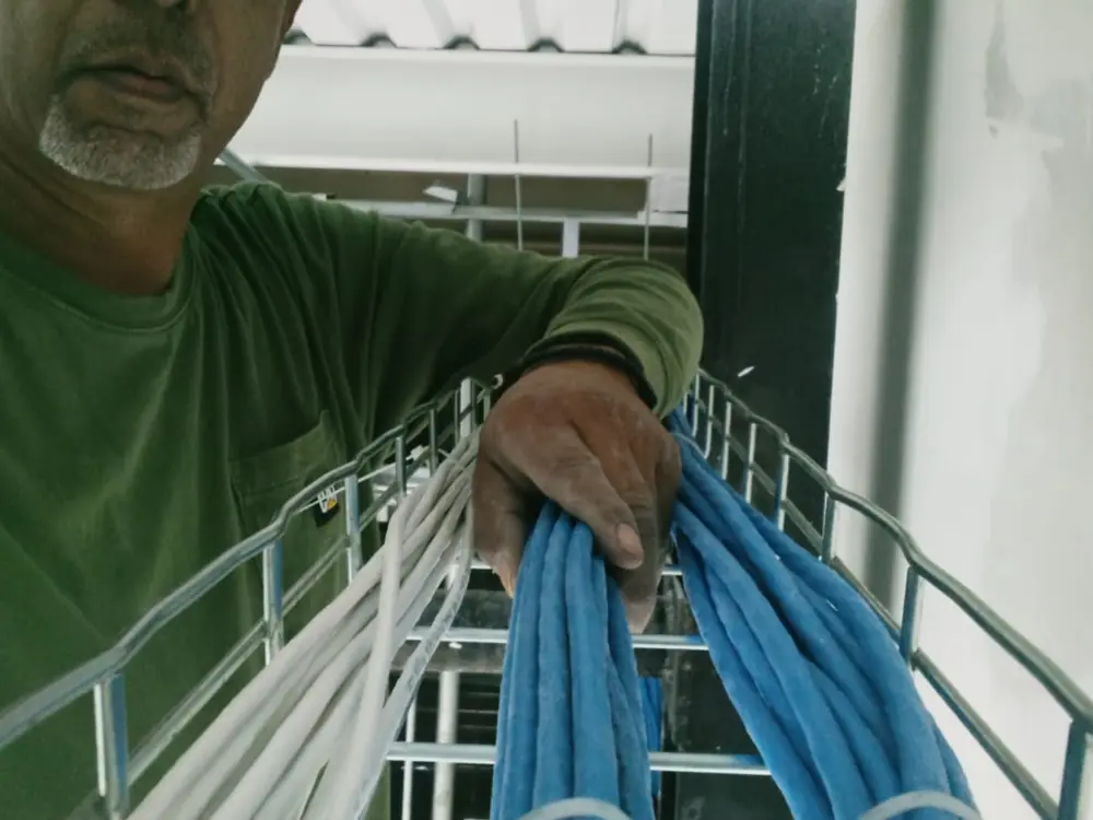 Conrado Orona sosteniendo un tendido de cables azules y blancos ordenados sobre una charola de techo