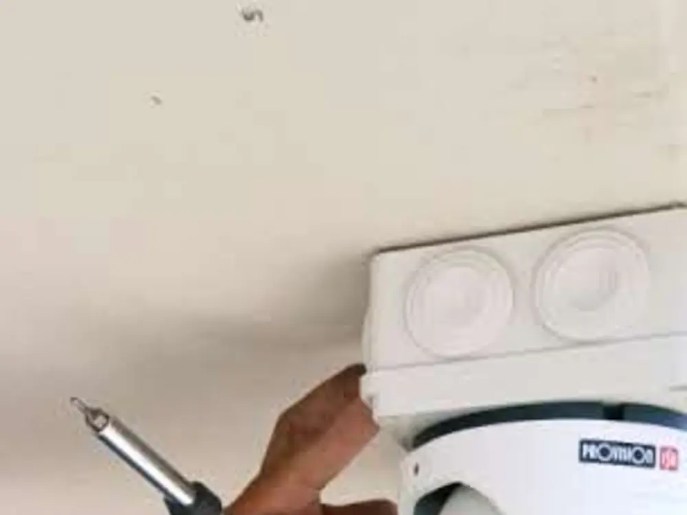 Conrado atornillando una cámara Provision ISR al techo de un porche