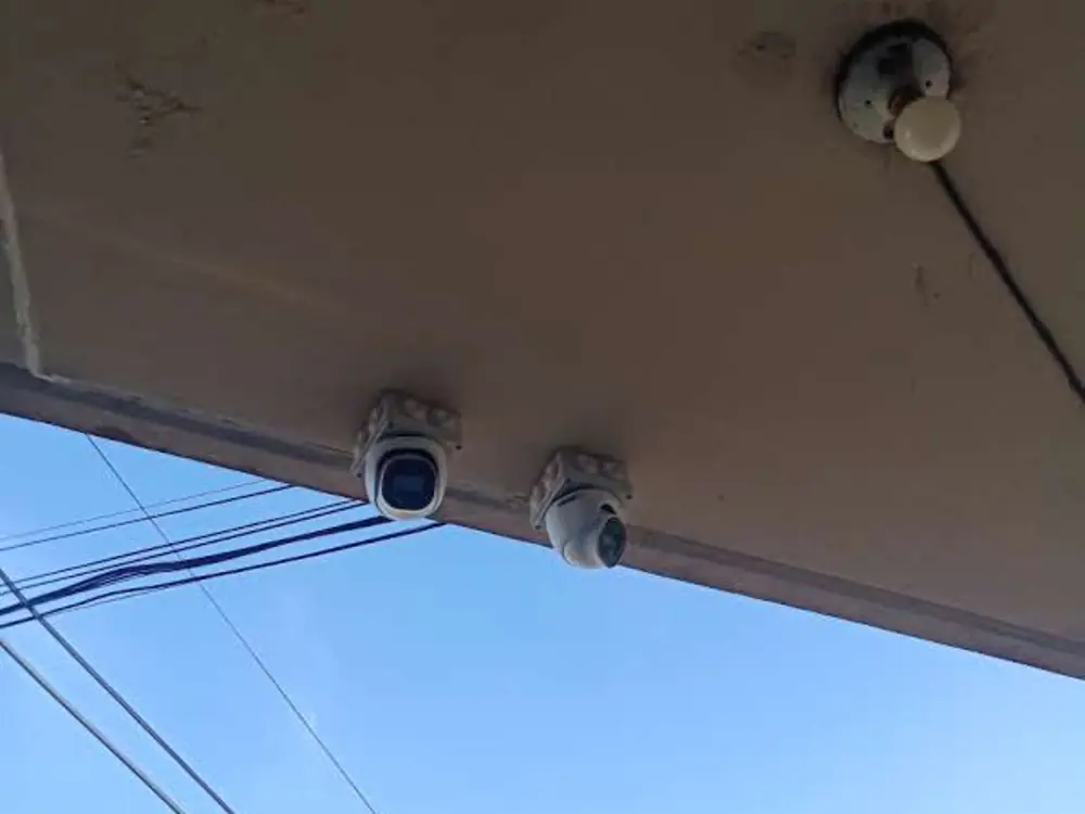 Dos cámaras montadas bajo el alero de un techo, una fija y una domo, apuntando a la calle