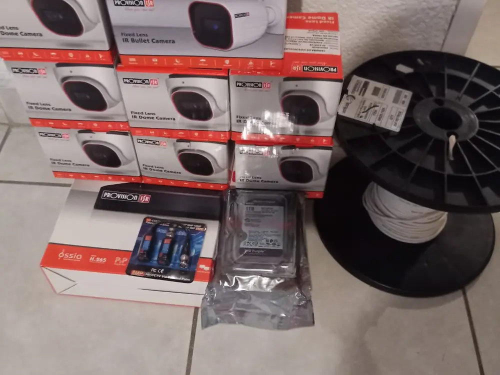 Cajas selladas de cámaras Provision ISR, un grabador, disco WD Purple y rollo de cable sobre el piso