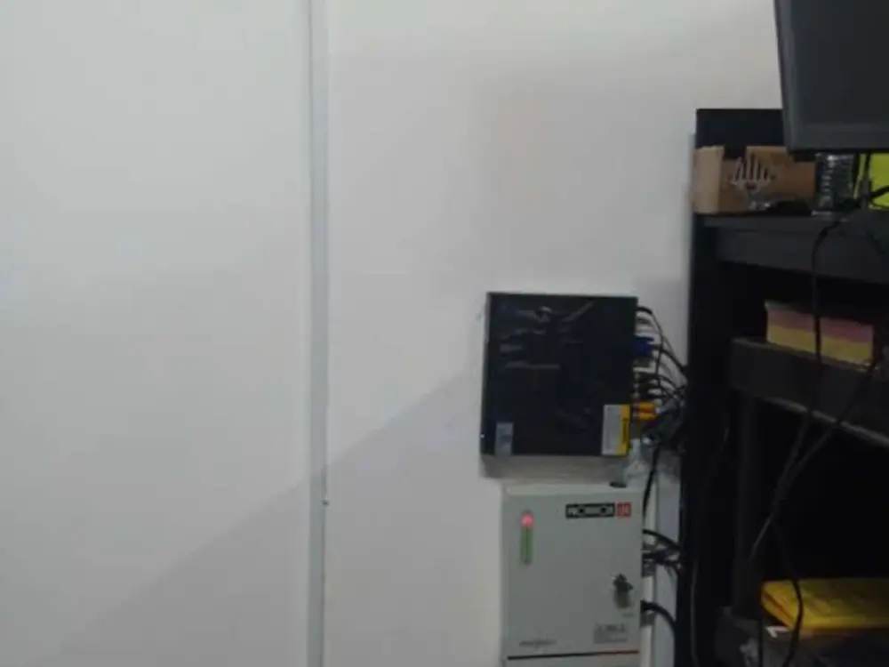Gabinete de respaldo montado en pared junto al equipo de grabación, con la canaleta subiendo a nivel