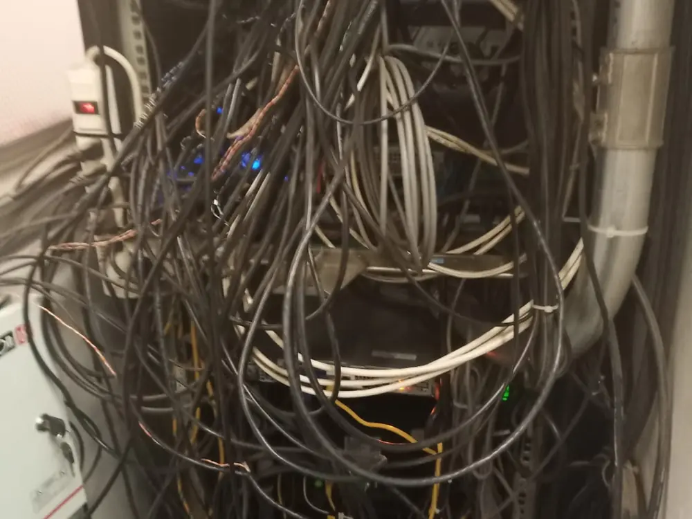 Rack con decenas de cables sueltos cruzados y enredados, sin sujeción ni orden