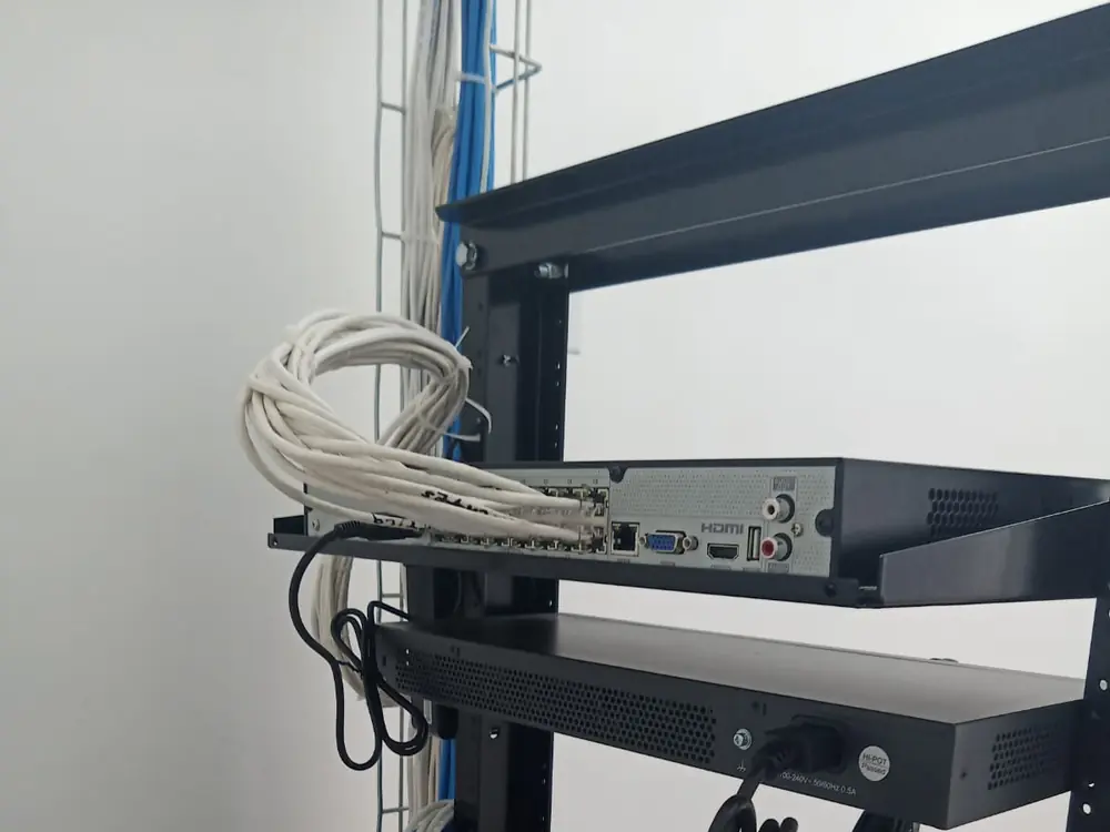 Rack abierto con NVR y switches montados en sus charolas y el cable sobrante enrollado a un lado